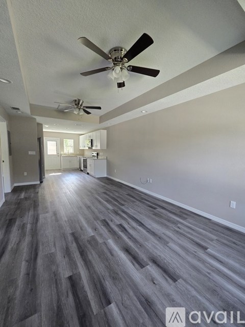 A spacious room with a ceiling fan and grey flooring.