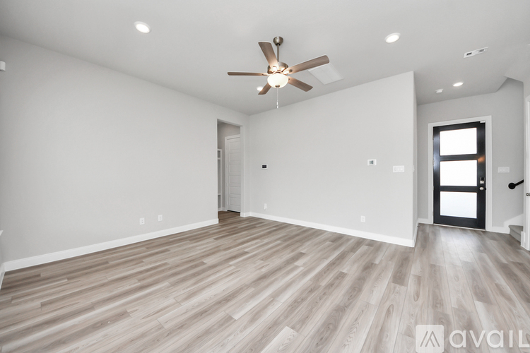 A spacious room with wooden flooring and a ceiling fan.
