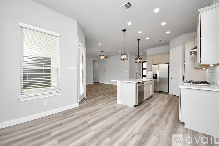 A spacious kitchen with white cabinets and a wooden floor.