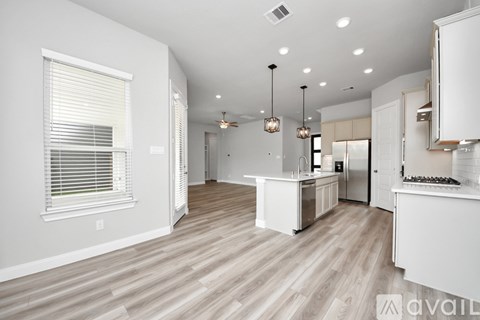 A spacious kitchen with white cabinets and a wooden floor.