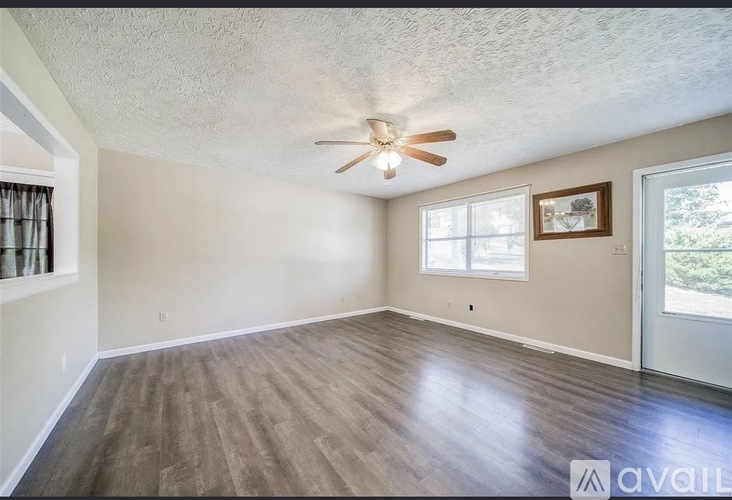A room with a ceiling fan and a window with a view of trees.