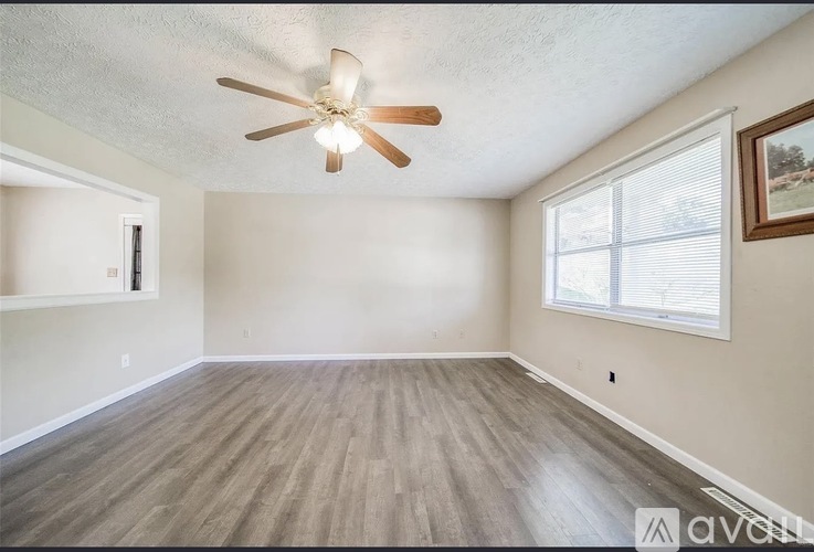 A room with a ceiling fan and wood flooring.