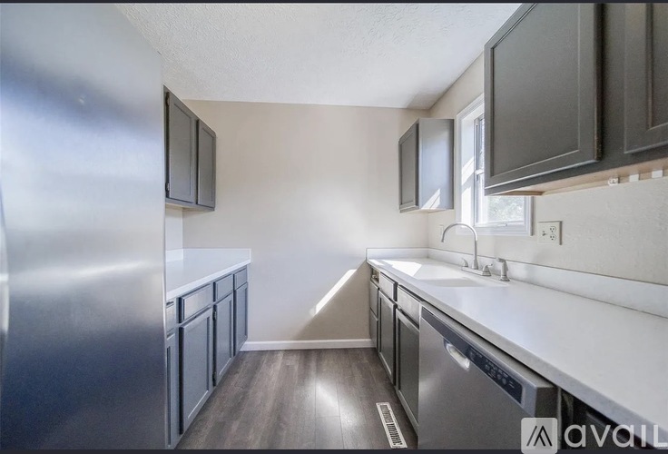 A kitchen with a stainless steel refrigerator and dark brown cabinets.
