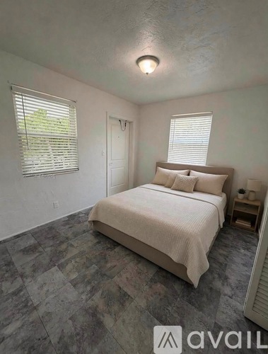A bedroom with a bed, nightstand, and window with blinds.