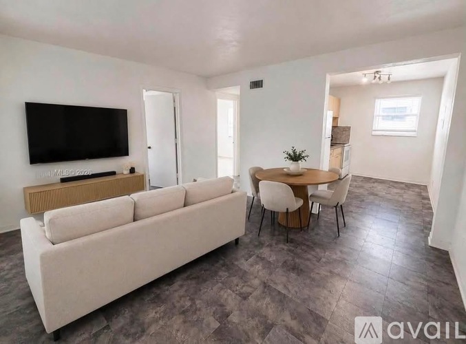 A living room with a white couch, a television, and a dining table.