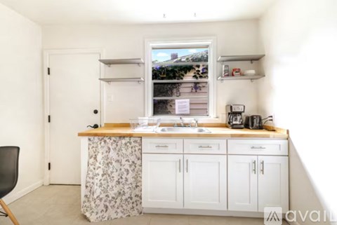 A kitchen with white cabinets and a window overlooking a street.