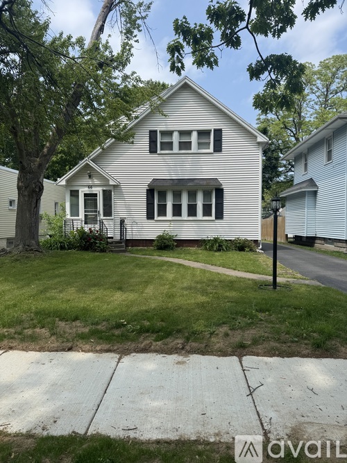A house with a white siding and black shutters is for sale.