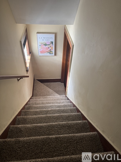 A staircase with a carpeted runner and a picture frame on the wall.