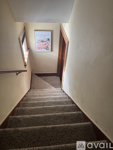 A staircase with a carpeted runner and a picture frame on the wall.