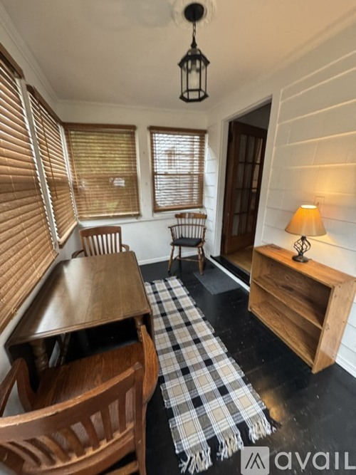 A room with a wooden table and chairs, a lamp, and a checkered rug.