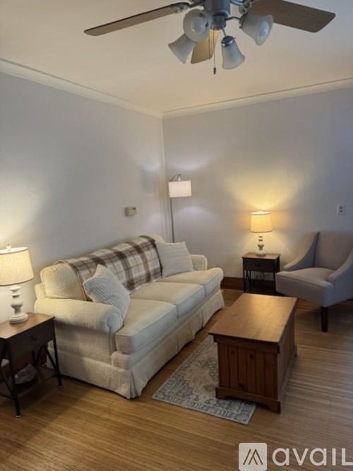 A living room with a couch, a chair, a coffee table, and a ceiling fan.