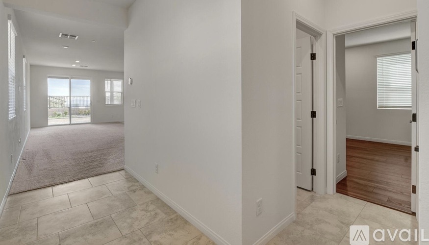 A spacious room with a carpeted floor and a door leading to another room.