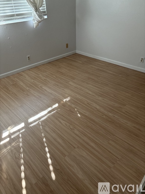 A room with wooden flooring and a window with blinds.
