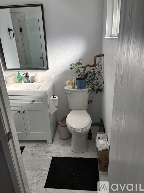 A bathroom with a toilet, sink, and mirror.