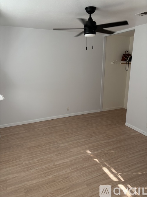 A room with a ceiling fan and wooden flooring.