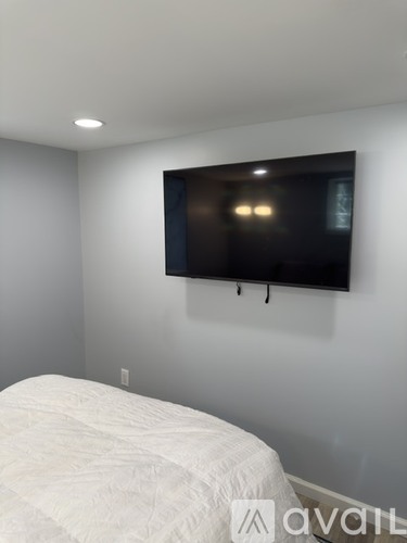 A bedroom with a bed and a flat screen TV mounted on the wall.
