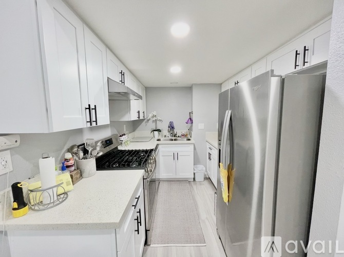 A kitchen with white cabinets and a stainless steel refrigerator.