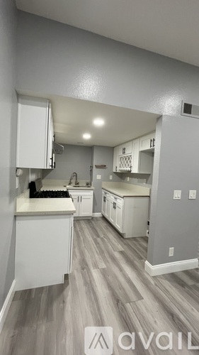 A kitchen with white cabinets and a wooden floor.
