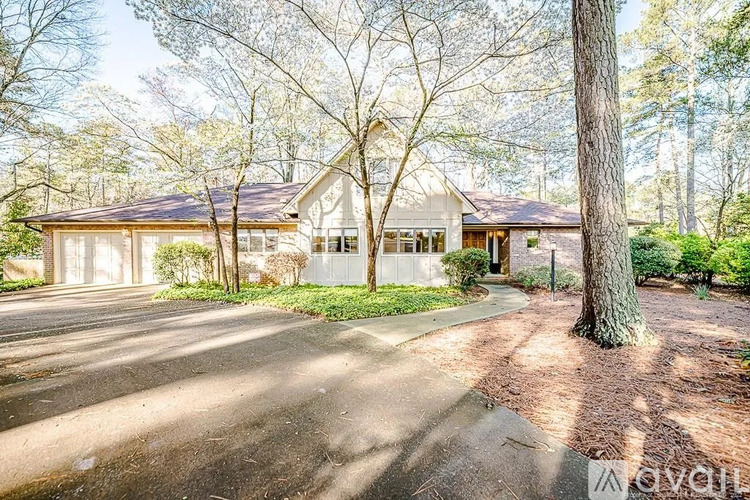 A house with a driveway and trees in the background.