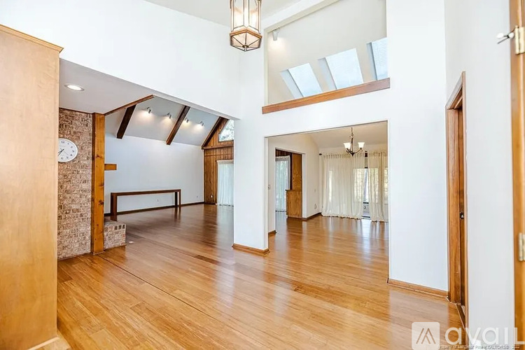 A large, open-concept living space with wooden floors and a skylight.