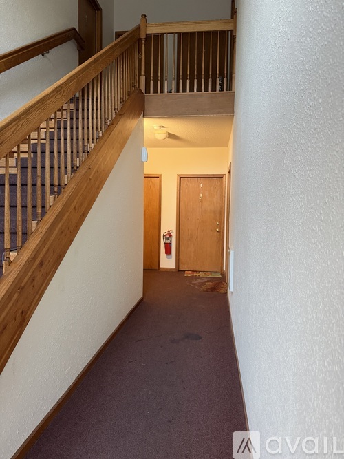 A hallway with a staircase on the left and a door on the right.
