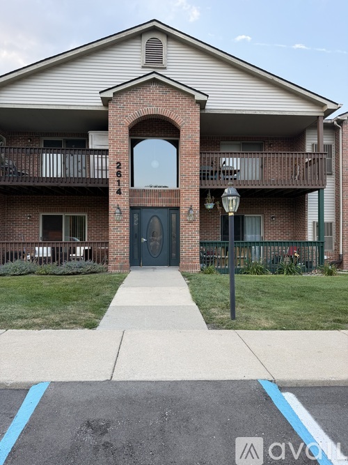 A brick building with a black door and a balcony with a lamp post.