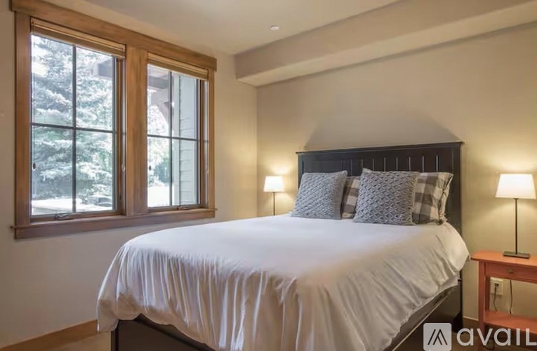 A bedroom with a large bed and a window overlooking trees.
