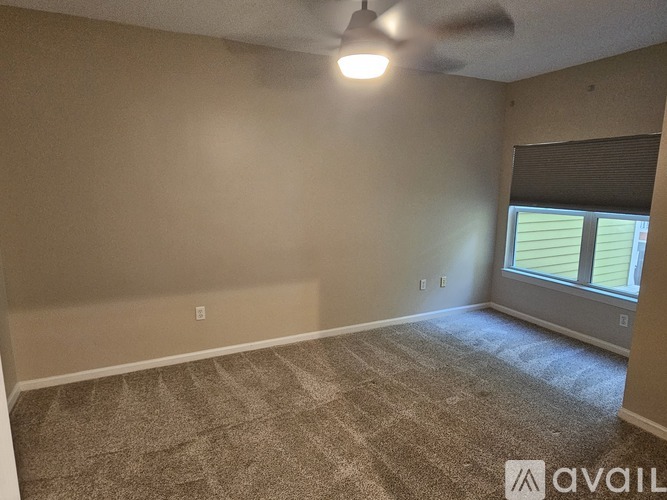 A room with a fan and a window with blinds.