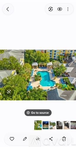 A pool surrounded by greenery and a building in the background.