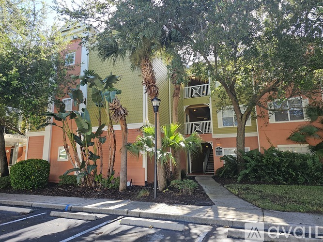 A building with a yellow and orange facade surrounded by greenery.