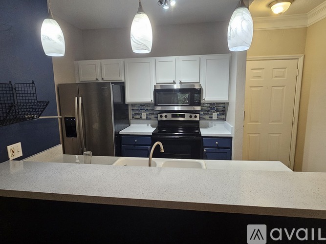 A kitchen with a refrigerator, microwave, and oven.