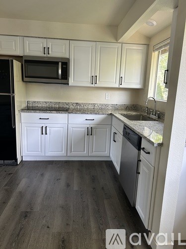 A kitchen with white cabinets and a granite countertop.