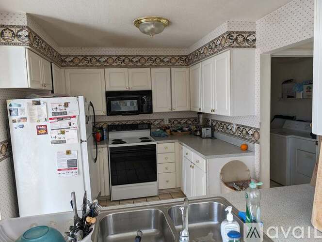 A kitchen with a white fridge, microwave, oven, and sink.