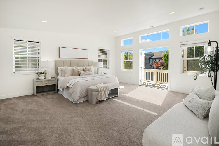 A bedroom with a large bed and a window overlooking a house.