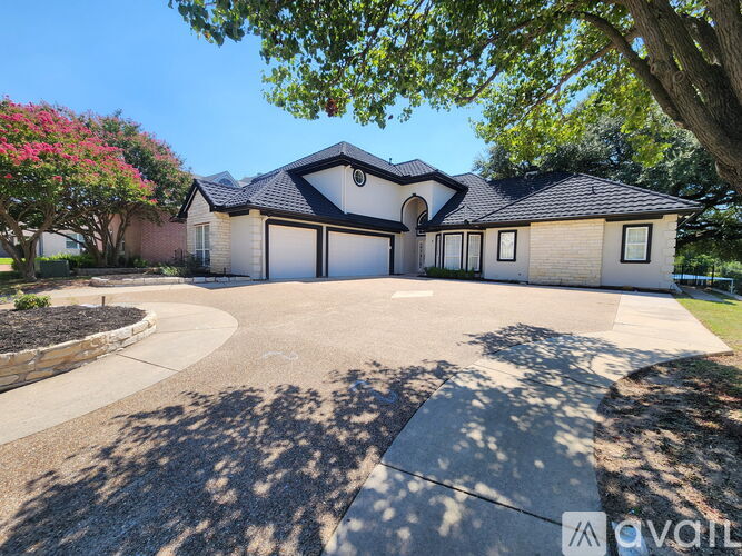 A house with a driveway and a tree with pink flowers.