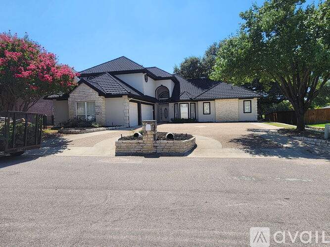A house with a driveway and a tree in front.