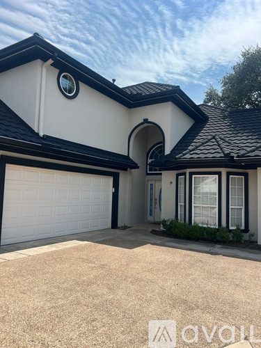 A white house with a black roof and a garage door.