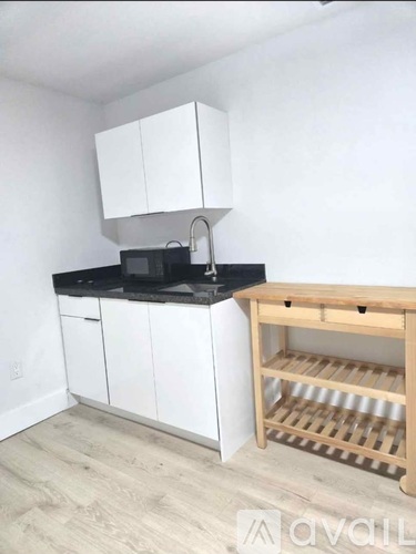 A kitchen with white cabinets and a wooden rack.