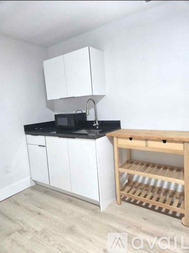A kitchen with white cabinets and a wooden rack.