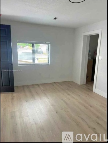 A room with wooden flooring and a window with blinds.