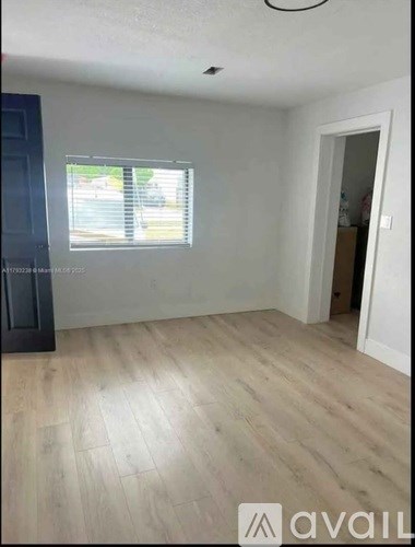 A room with wooden flooring and a window with blinds.