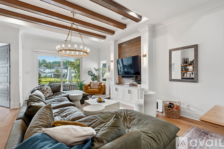 A living room with a large sectional sofa and a television on a white stand.