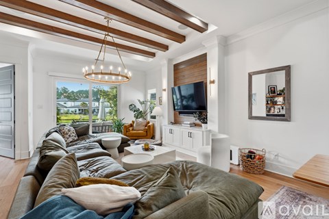 A living room with a large sectional sofa and a television on a white stand.