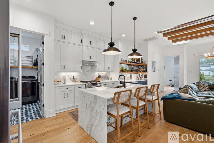 A modern kitchen with white cabinets and a marble island.