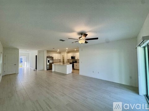 A spacious living room with a ceiling fan and lighting fixture.