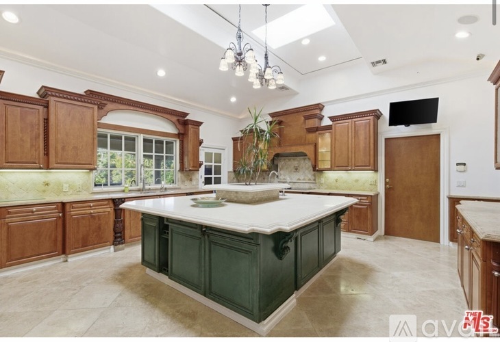 A kitchen with a green island and wooden cabinets.