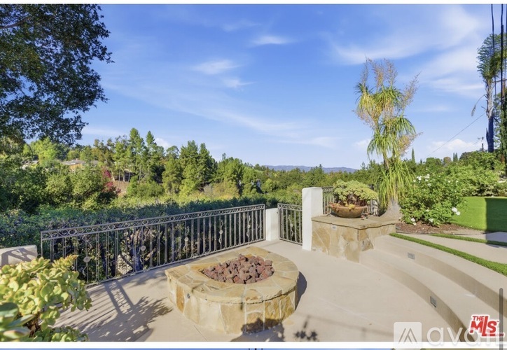 A patio with a fire pit and a metal fence.