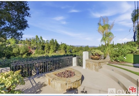 A patio with a fire pit and a metal fence.