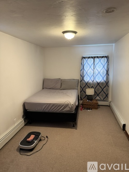 A small bedroom with a bed, window, and a rug.