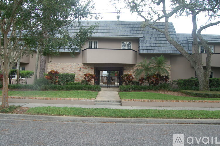 A house with a brown roof and a tree in front.